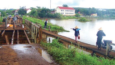 The bridge over the reservoir in Cu Kpo Commune of Krong Buk District in Dak Lak Province has been destroyed, forcing local people to use a make-shift bridge (R) (Photo: SGGP) The bridge over the reservoir in Cu Kpo Commune of Krong Buk District in Dak Lak Province has been destroyed, forcing local people to use a make-shift bridge (R) (Photo: SGGP)